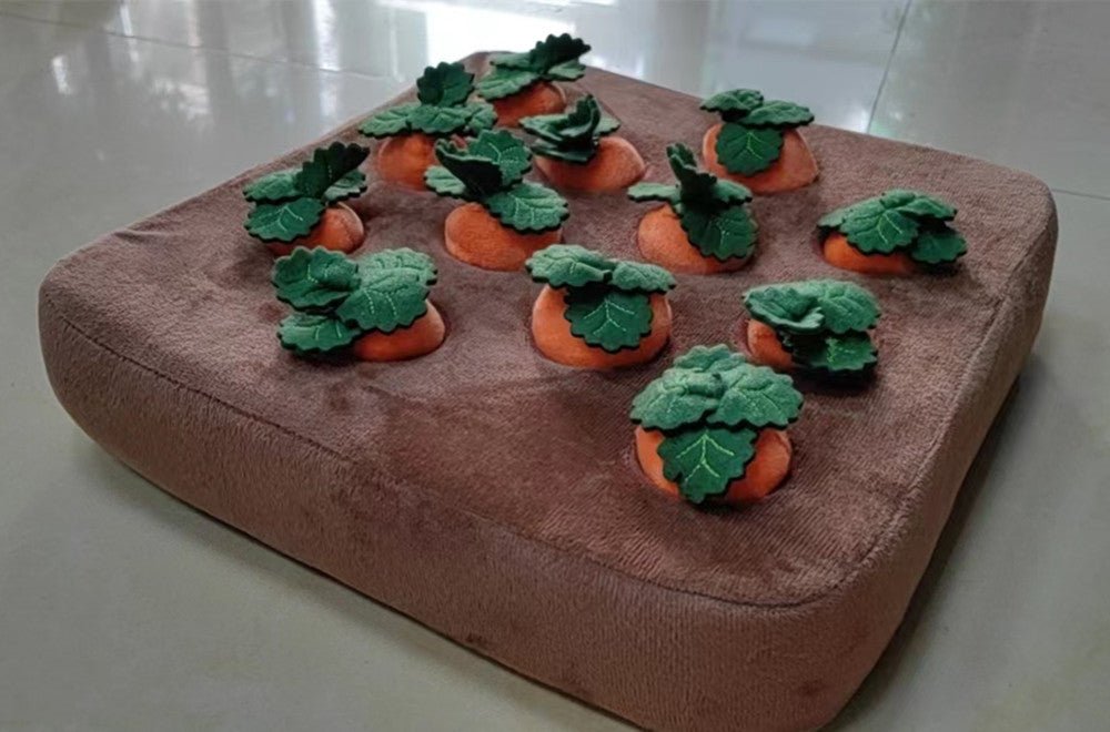 Carrot puzzle mat toy with plush orange carrots and green leaves arranged on tan fabric for interactive pet foraging games.