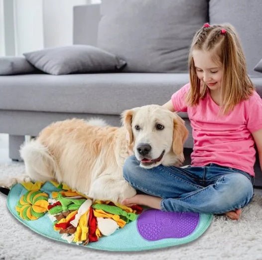 Girl playing with golden retriever using interactive snuffle pad foraging toy on carpet